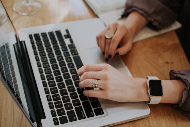 Hands typing on a silver laptop researching property management companies